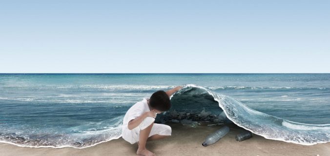 Bambino sulla spiaggia che osserva il mare inquinato